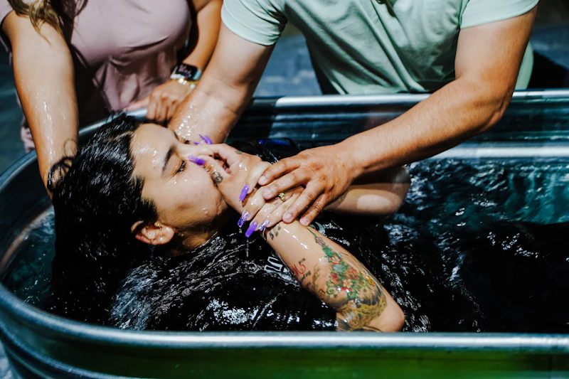 Three people standing in a baptism tub full of water