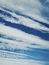 Cloud formations stretch across a rich blue sky, with varying textures and patterns creating a dynamic and serene scene.