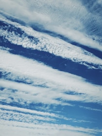 Cloud formations stretch across a rich blue sky, with varying textures and patterns creating a dynamic and serene scene.