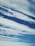 Cloud formations stretch across a rich blue sky, with varying textures and patterns creating a dynamic and serene scene.