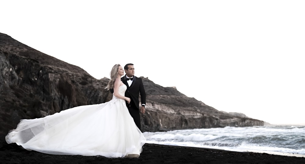 bride and groom standing on rock formation near body of water during daytime