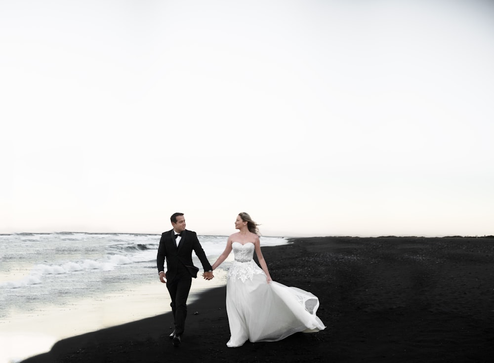 bride and groom walking on beach during daytime