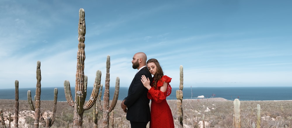 man in black suit jacket standing beside woman in red dress