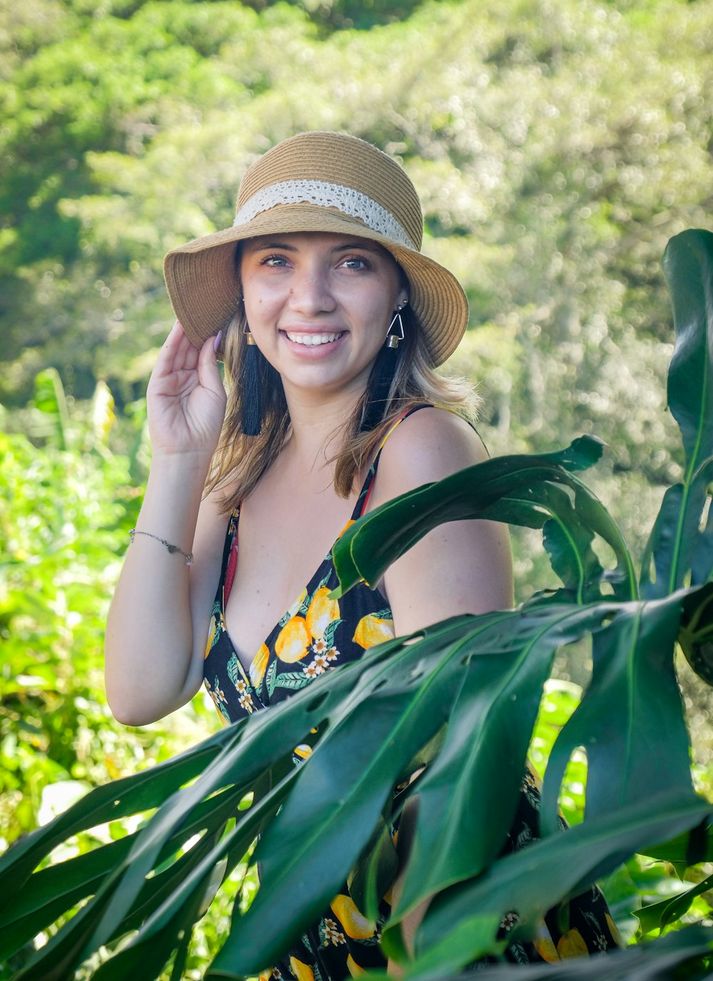 woman in brown hat and yellow and black floral sleeveless dress