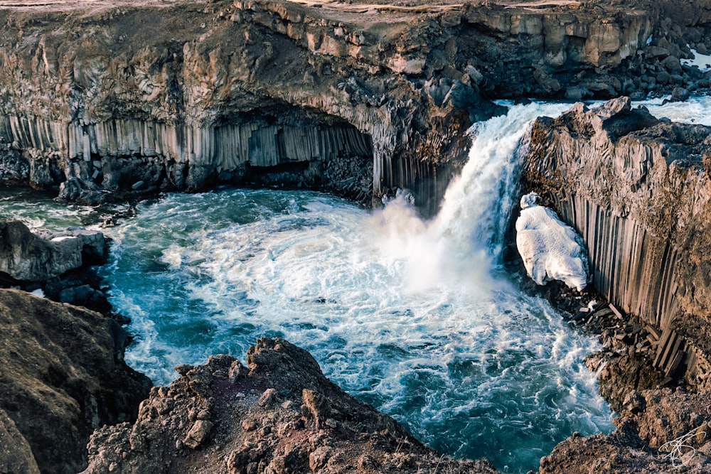 water falls on rocky mountain during daytime