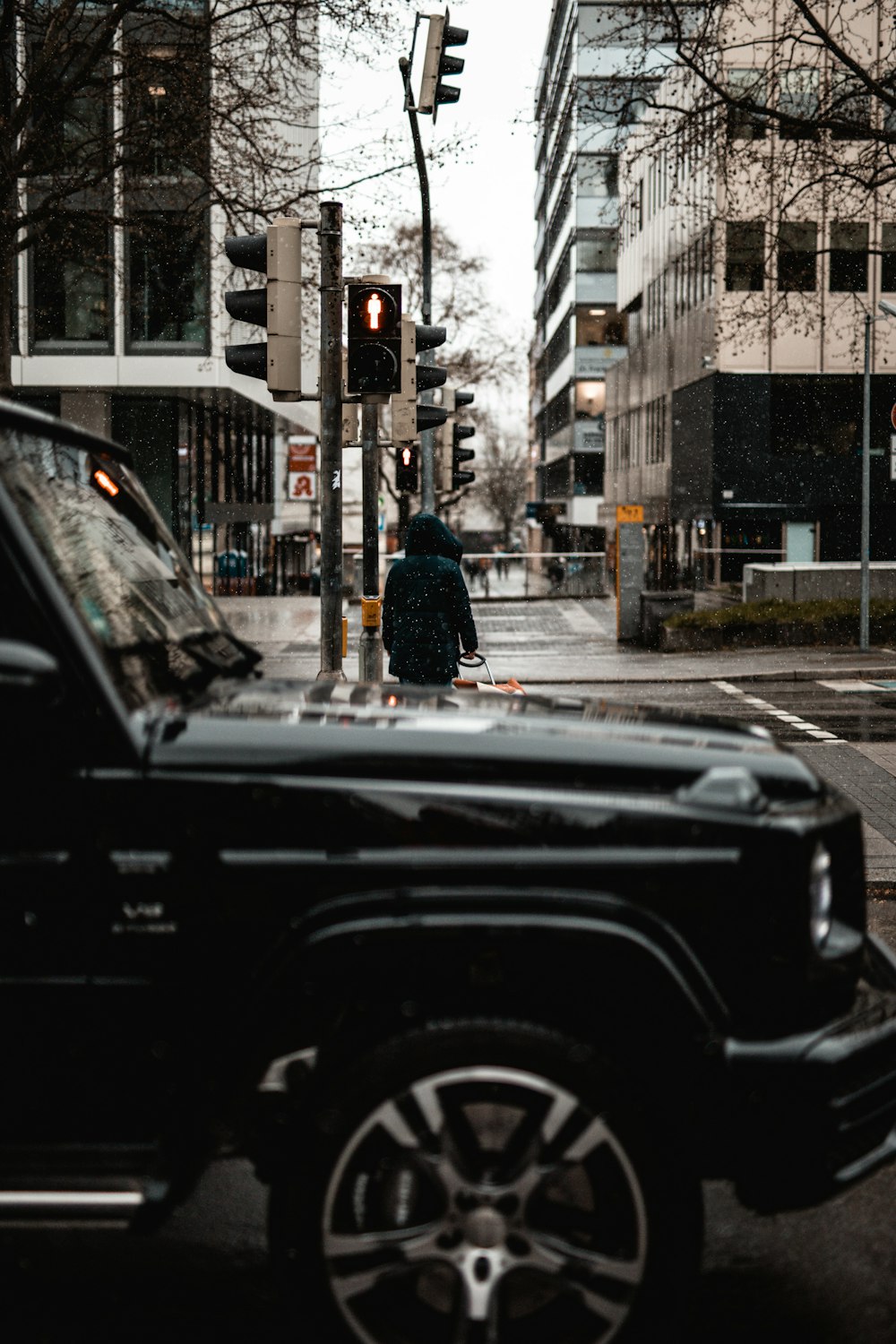 man in black jacket standing beside black car during daytime