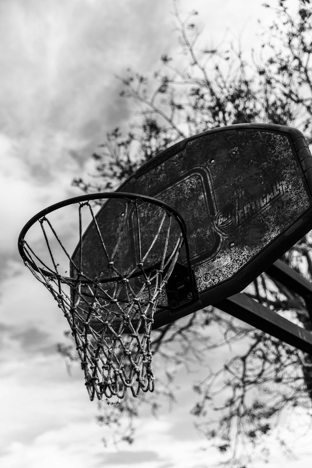 basketball hoop under cloudy sky in grayscale photography