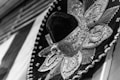 A detailed close-up of a traditional sombrero adorned with intricate embroidery and beading. The ornate patterns and designs on the hat are highlighted through the use of contrasting textures and detailed craftsmanship.