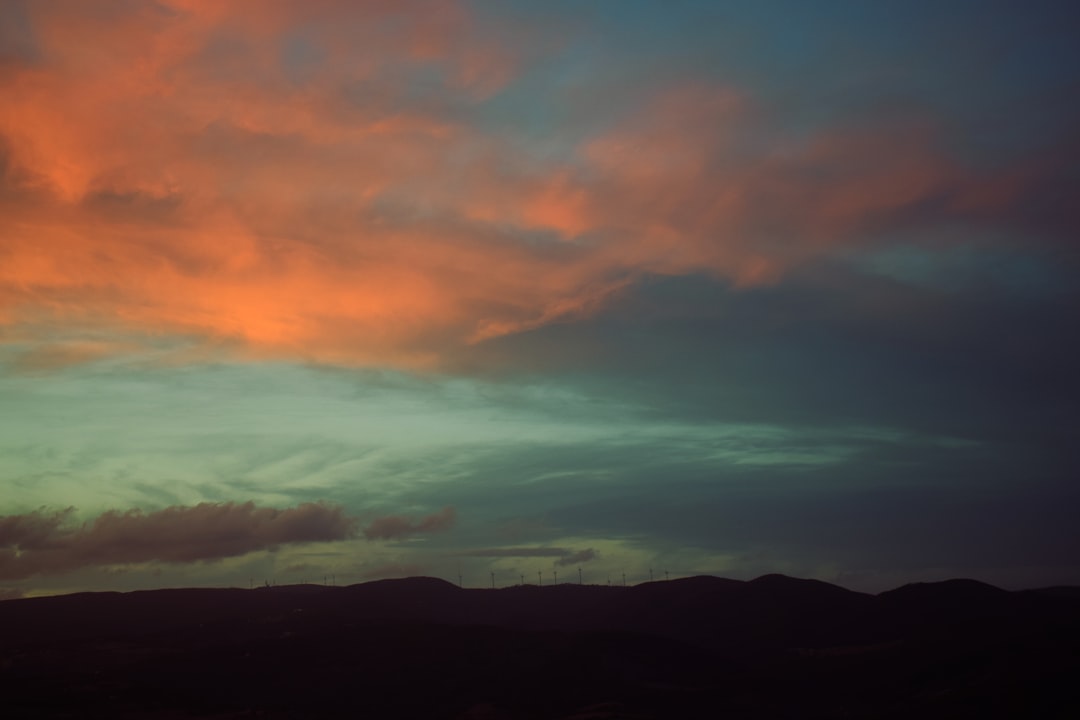 silhouette of mountain under orange and gray clouds