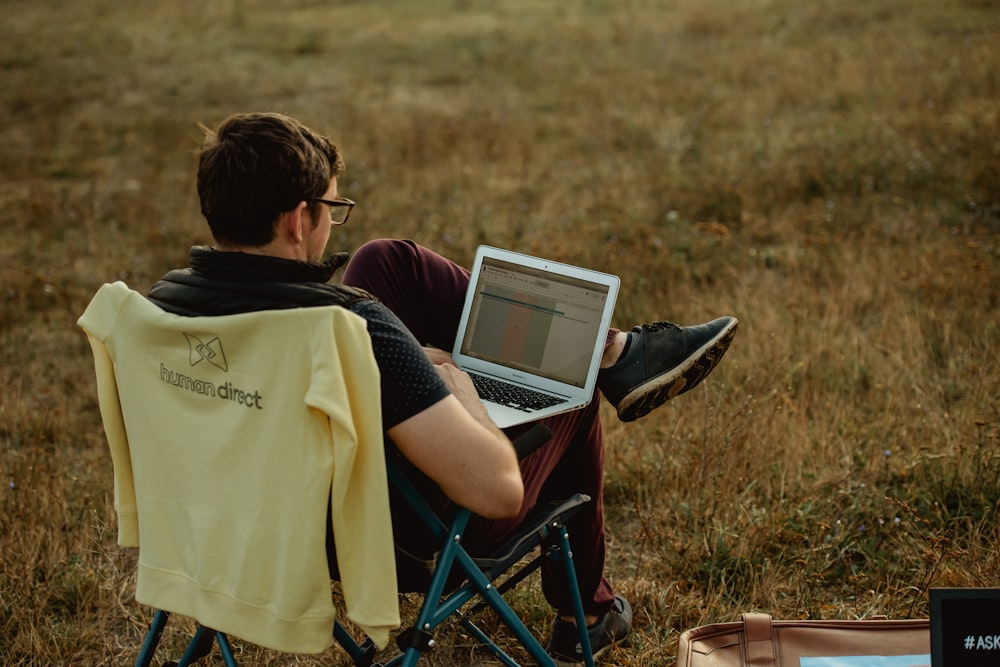 Junge im gelben T-Shirt sitzt auf blau-schwarzem Campingstuhl