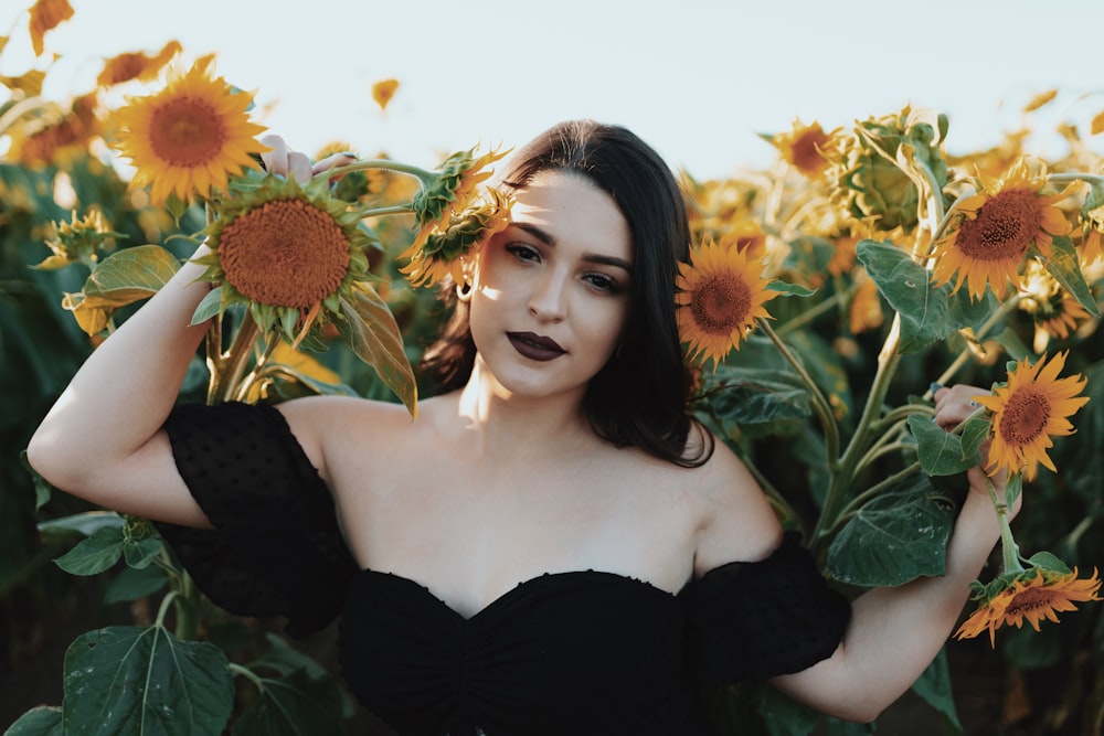 woman in black off shoulder dress standing on sunflower field during daytime