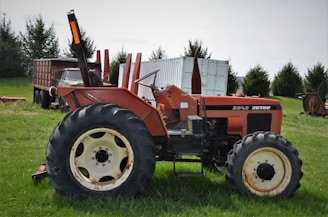 A red Zetor tractor parked in a sunny open field.