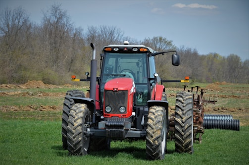 red tractor on green grass field during daytime