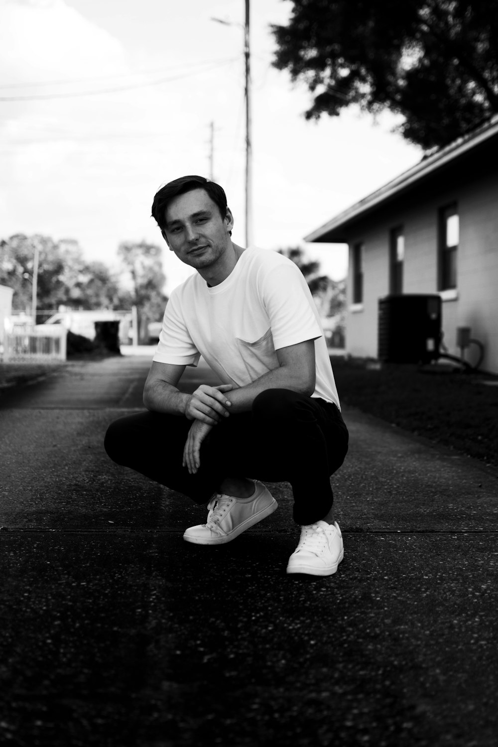 man in white crew neck t-shirt and black pants sitting on the ground