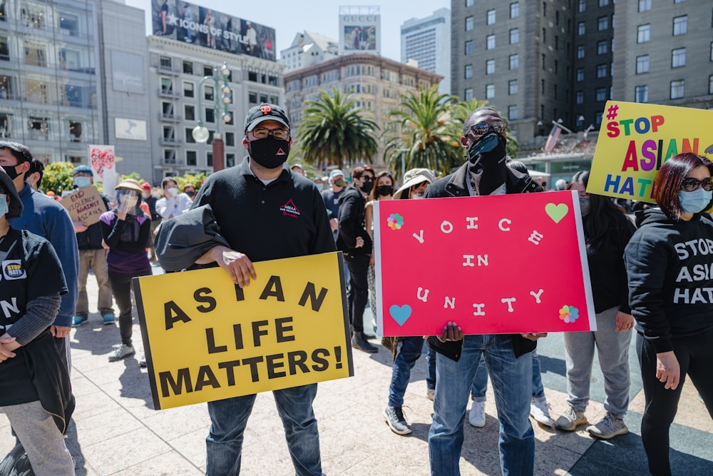 man in black long sleeve shirt holding red and yellow signage