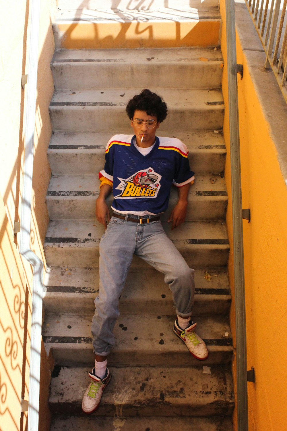 man in blue and red crew neck t-shirt sitting on yellow staircase