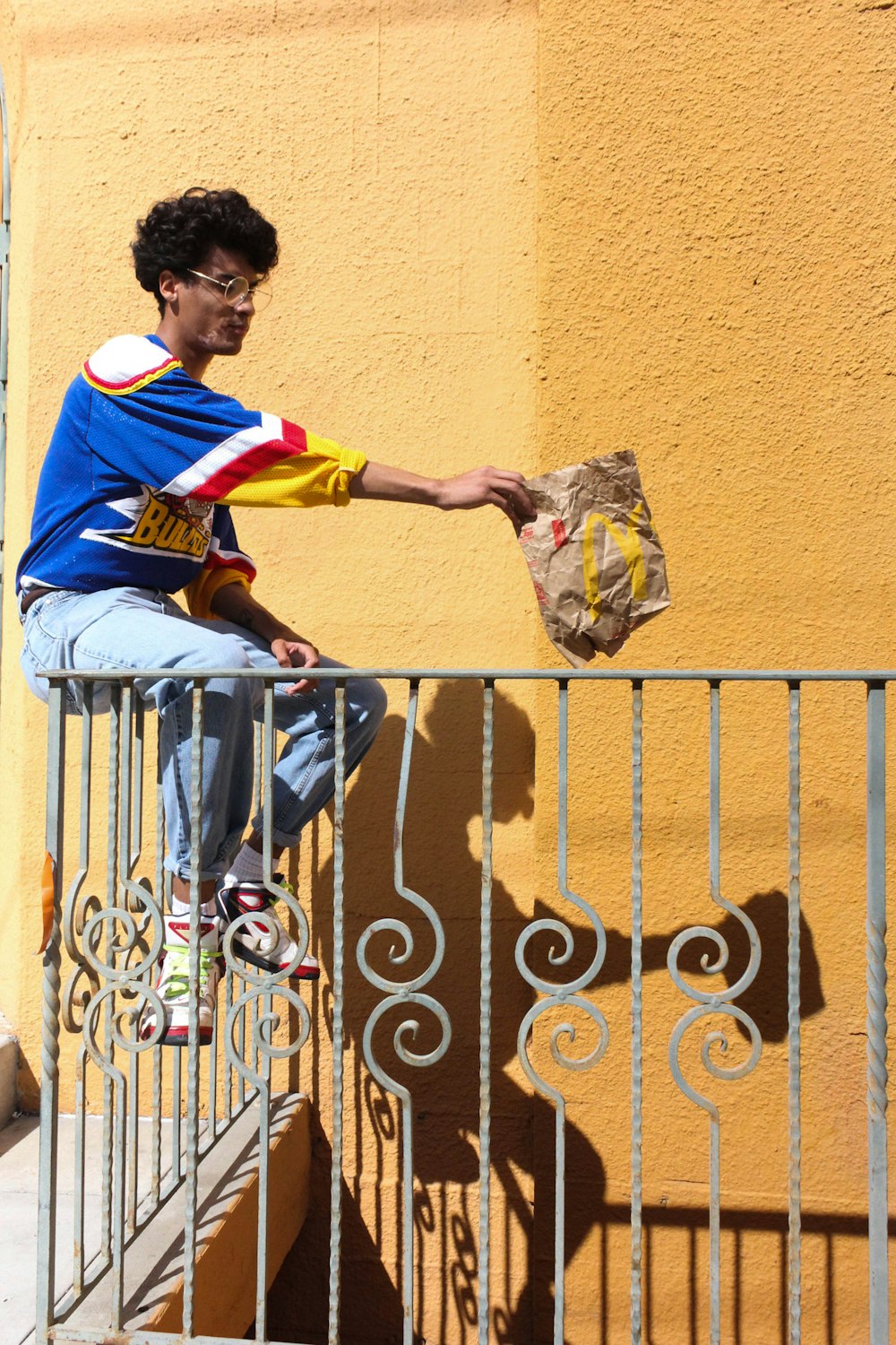 man in blue and white crew neck t-shirt and blue denim jeans sitting on gray