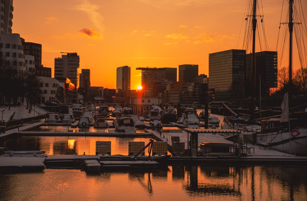 the sun is setting over a marina in a city