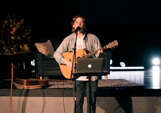man in brown coat singing on stage