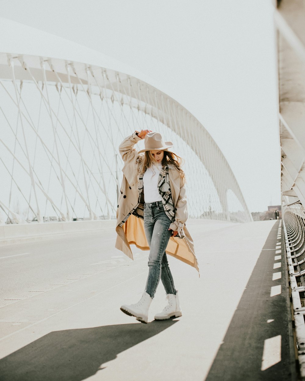 woman in brown coat and blue denim jeans standing on white concrete floor during daytime