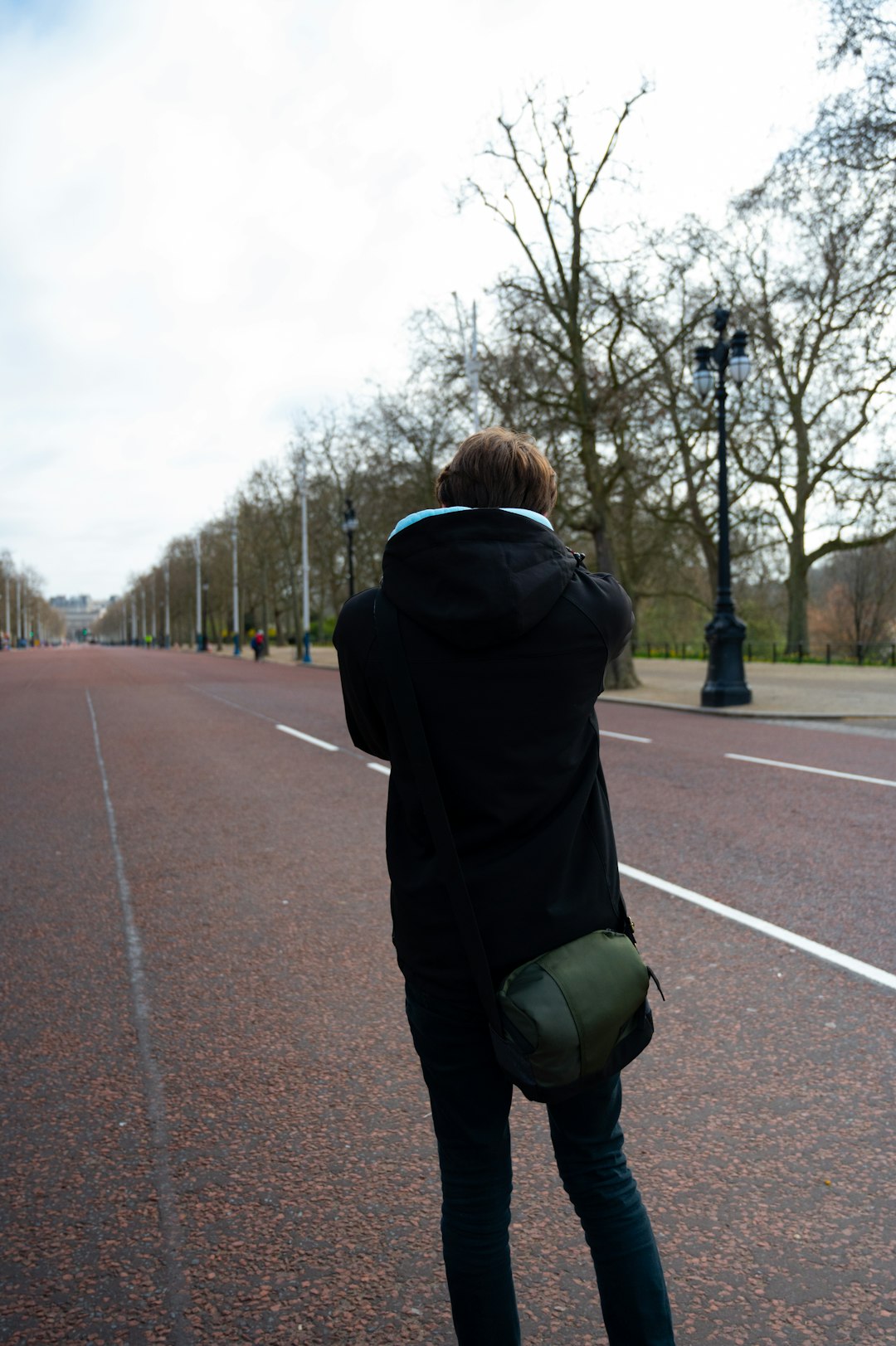 person in black hoodie walking on road during daytime