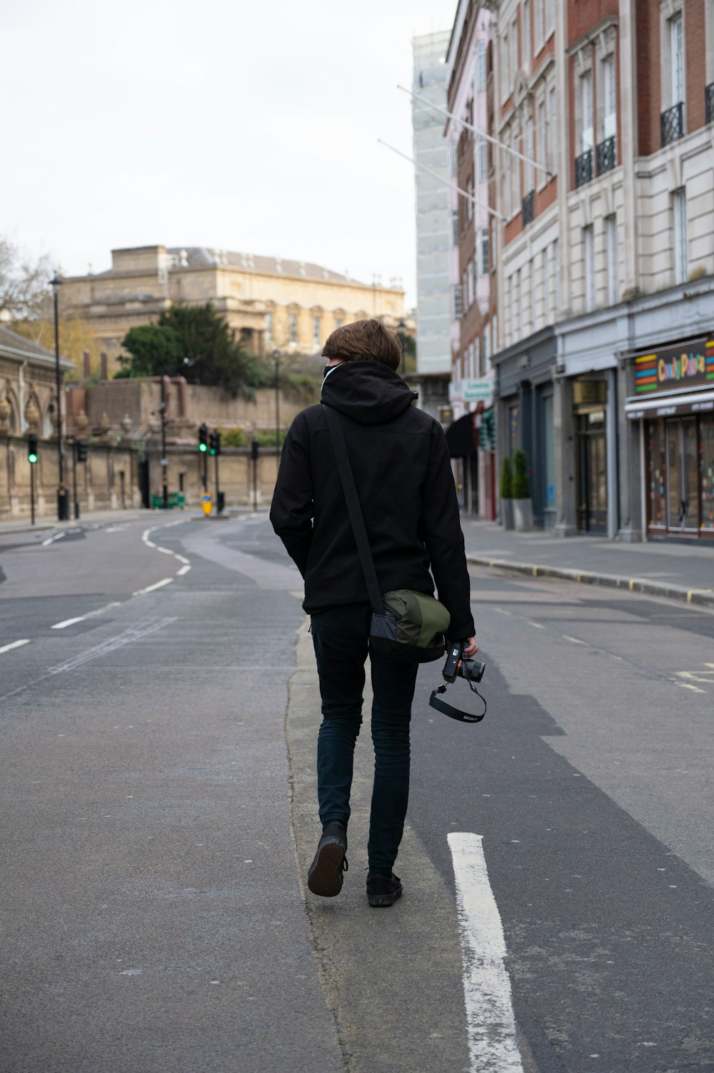 man in black hoodie and black pants walking on pedestrian lane during daytime