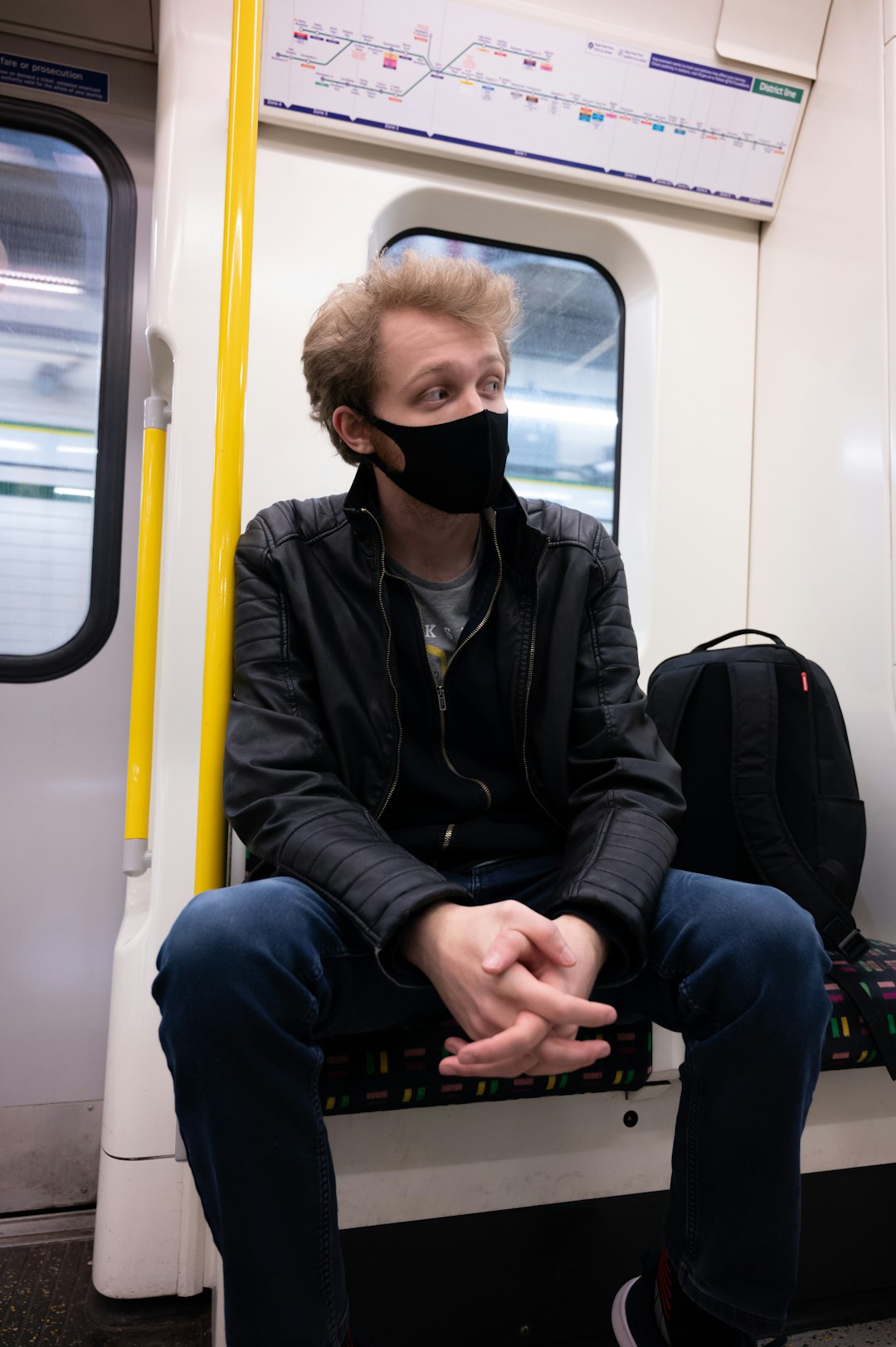 man in black jacket wearing black sunglasses sitting on train seat