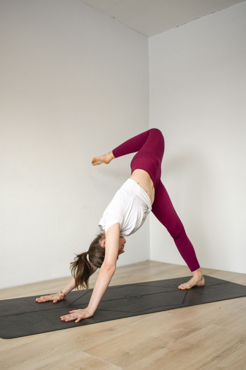 woman in white tank top and purple leggings doing yoga