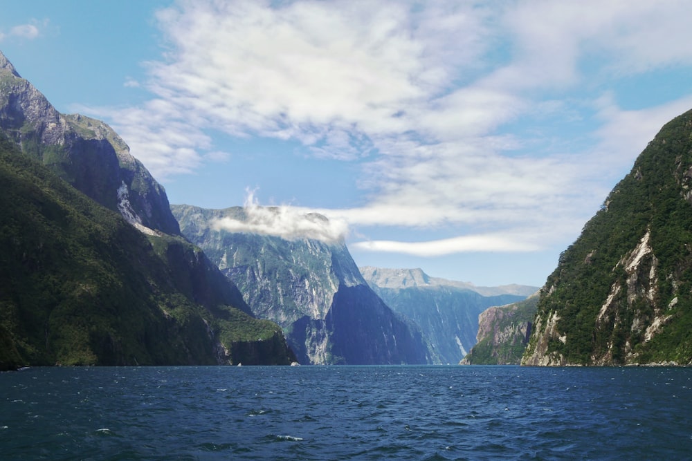 green and white mountain beside body of water under blue sky during daytime