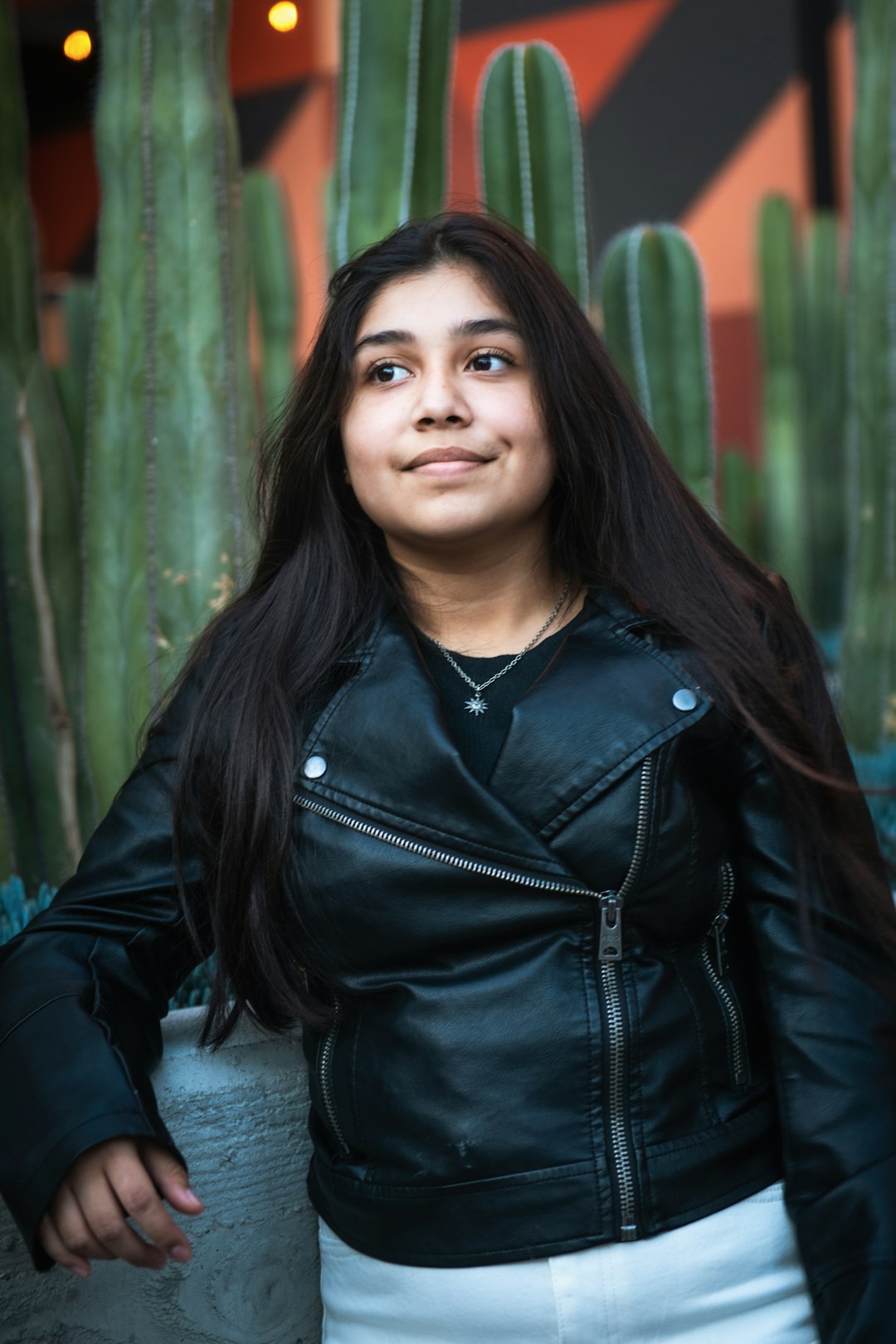 woman in black leather jacket sitting on concrete bench