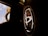 A close-up view of a car's steering wheel displaying a prominent Toyota logo in a well-lit interior. The background is blurred, showing part of the windshield and a glimpse of the blue sky.