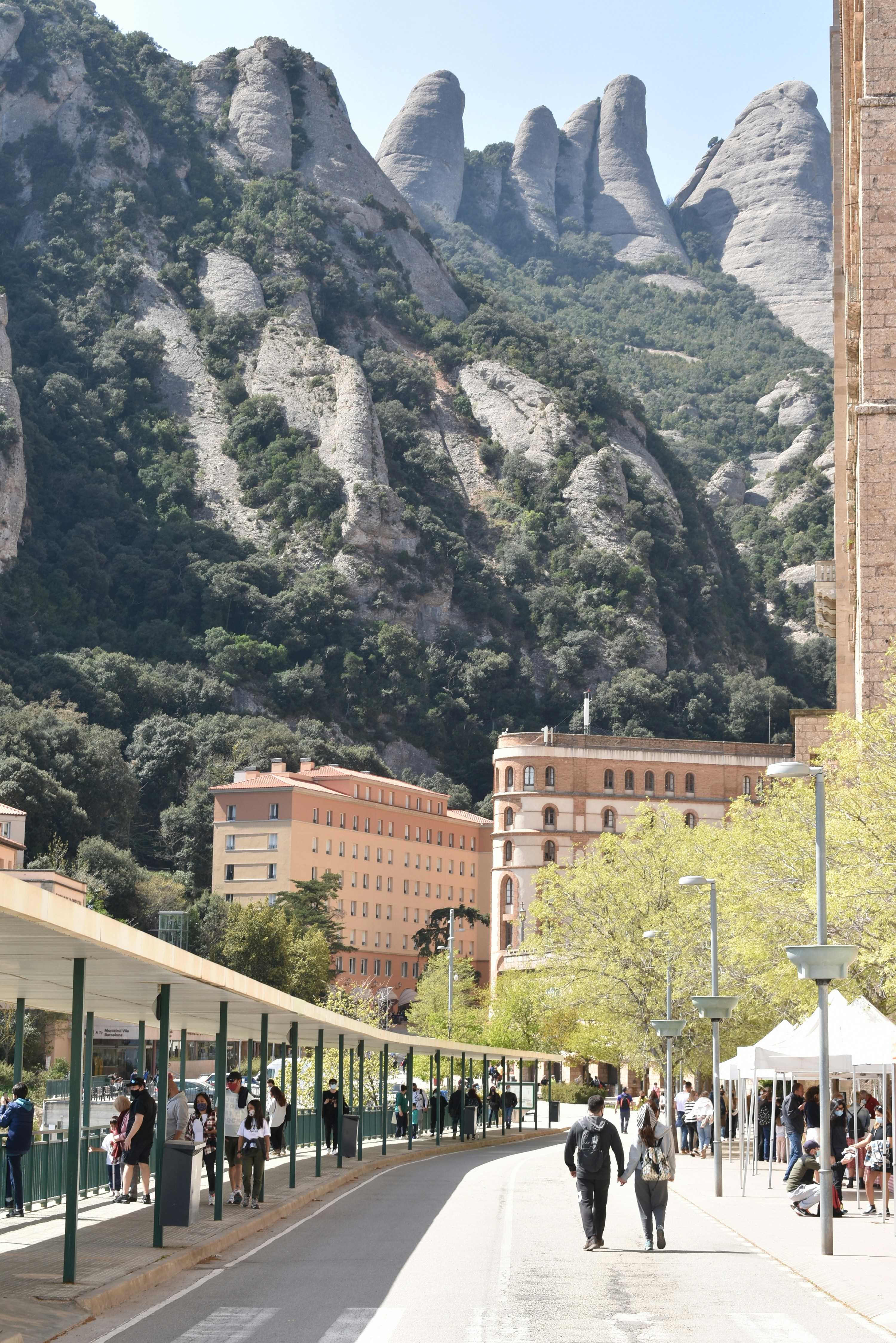 people walking on sidewalk near mountain during daytime