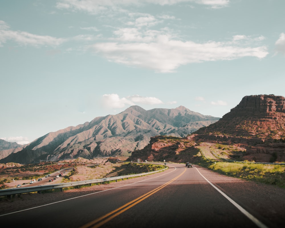 black asphalt road near brown mountains during daytime