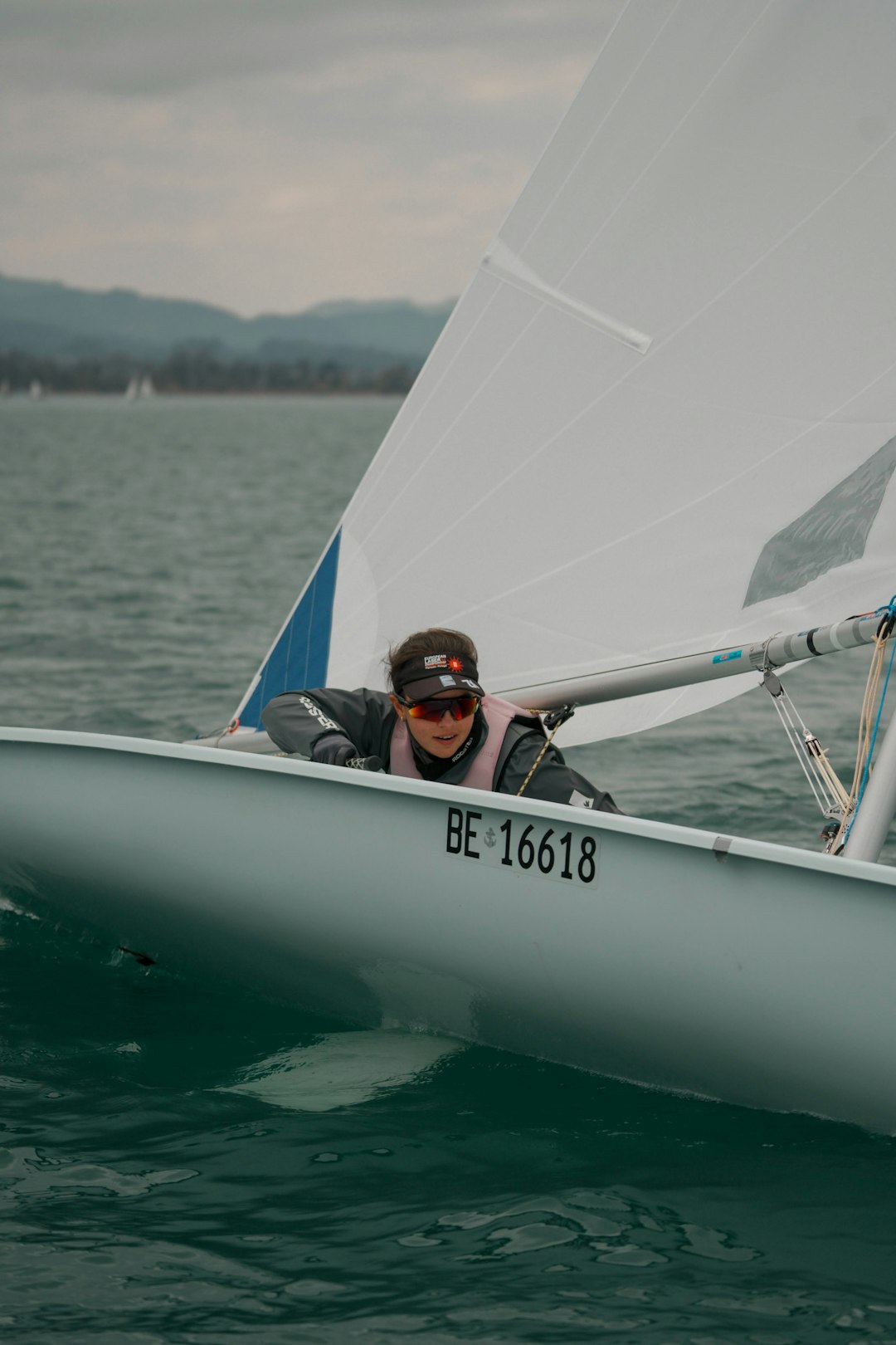 man in blue and black jacket riding on white boat during daytime