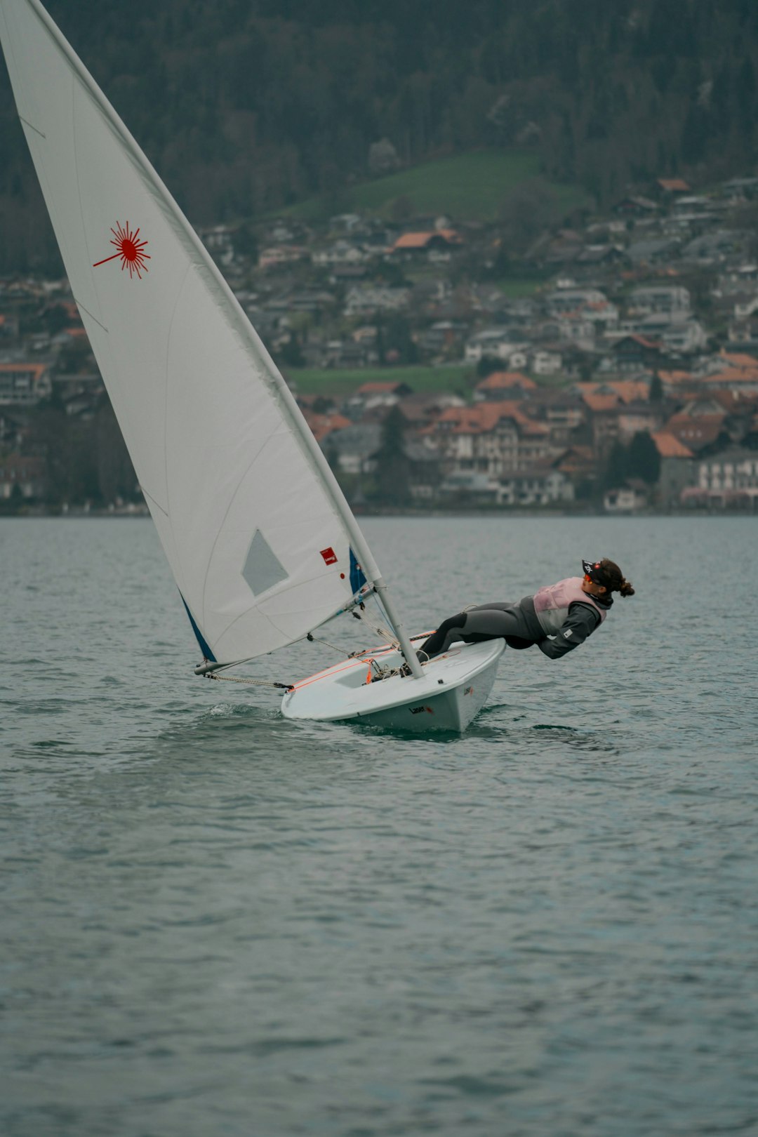 man in black jacket and black pants riding white and red sail boat on sea during