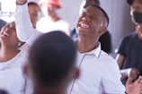 A joyful individual raising hands in praise during a worship session.