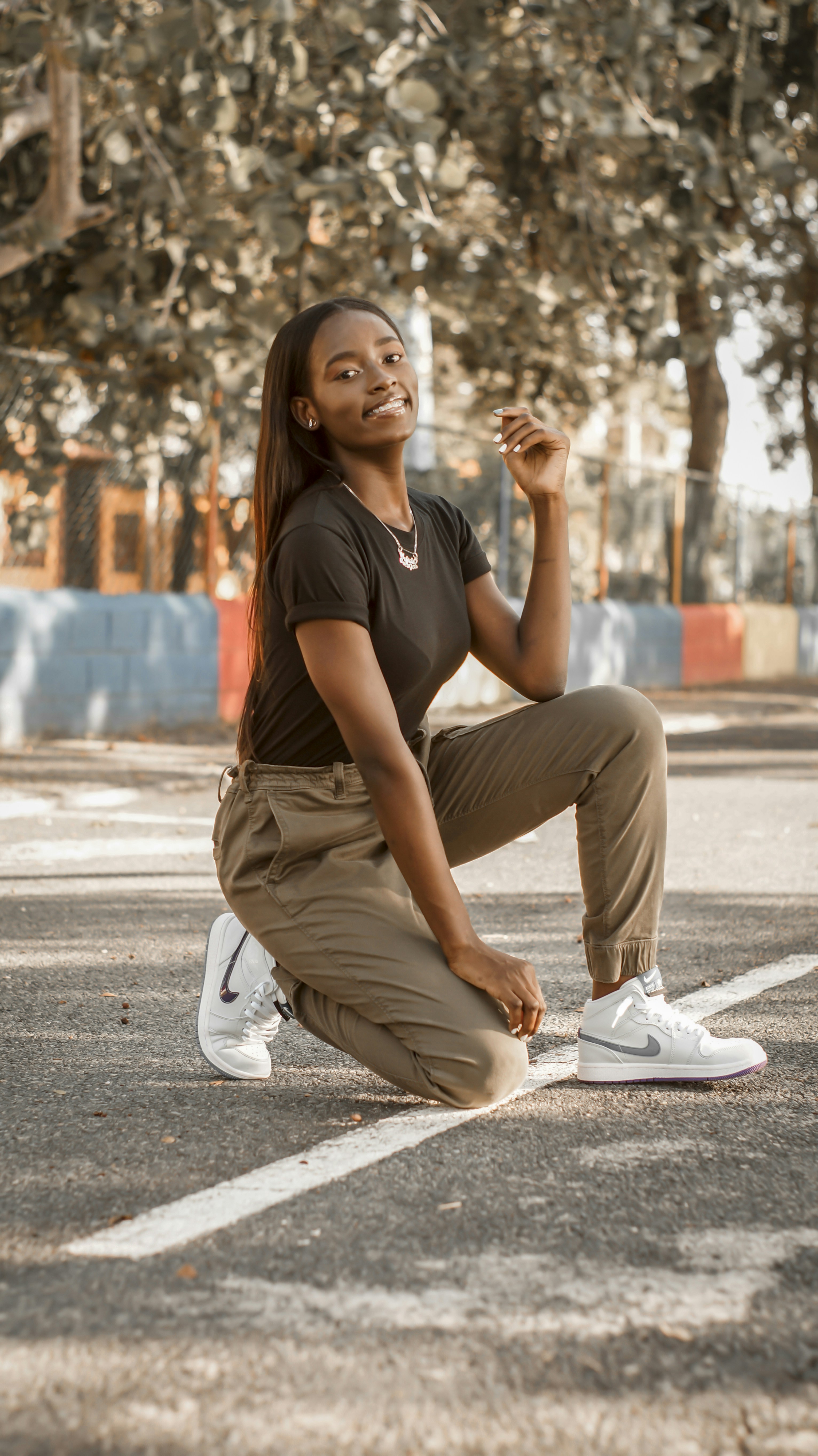 woman in black t-shirt and brown pants sitting on concrete floor during daytime