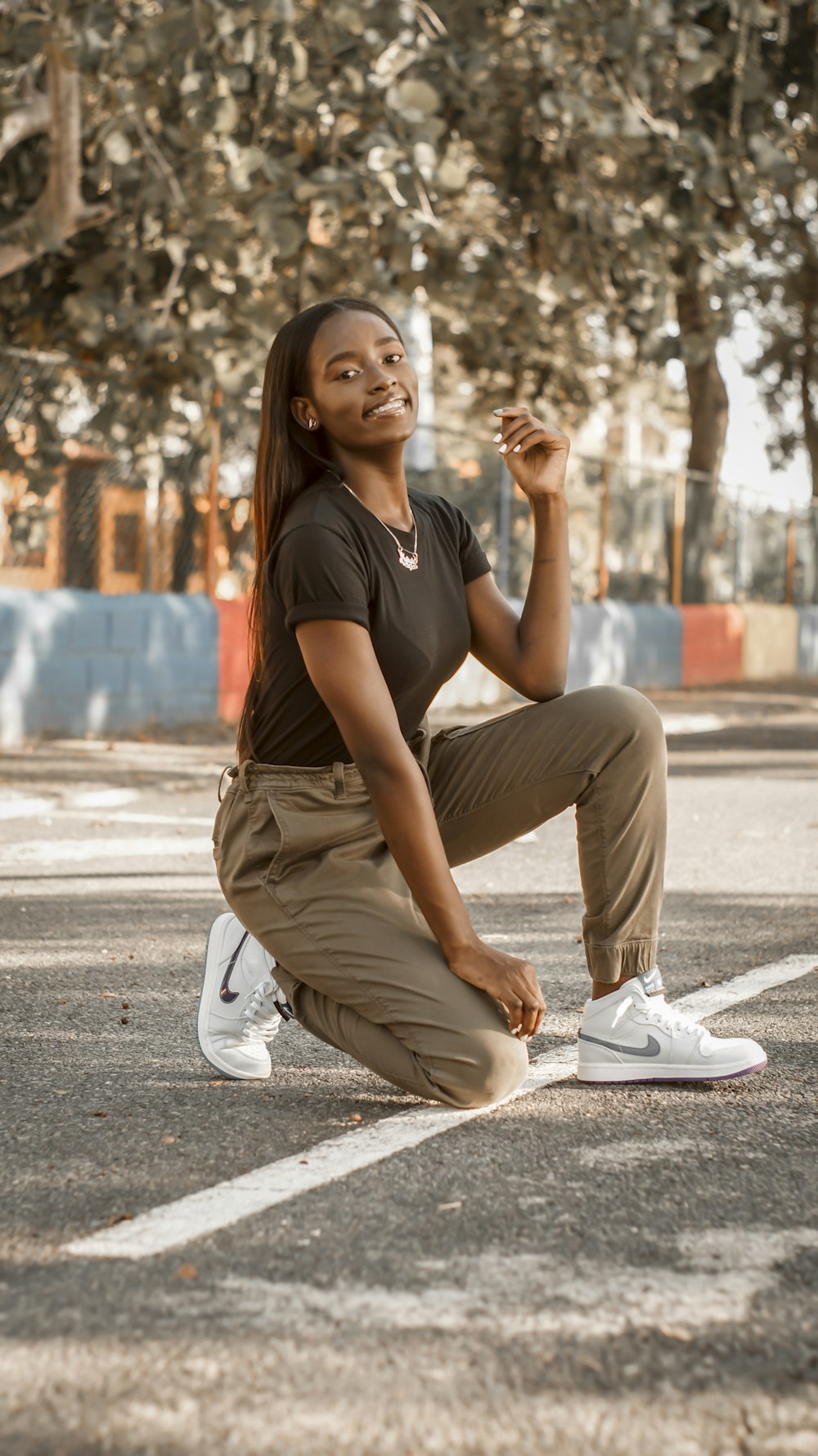 woman in black t-shirt and brown pants sitting on concrete floor during daytime