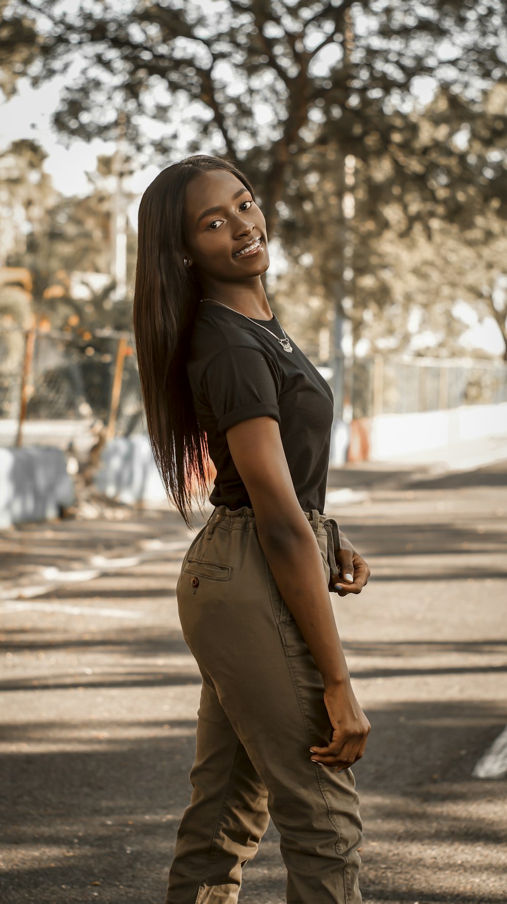 woman in black shirt and brown pants standing on road during daytime