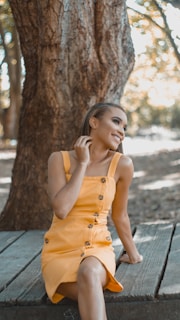 A bright yellow sundress hanging from a tree branch, fluttering gently in a light breeze.