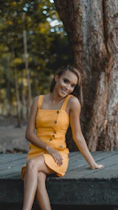 woman in orange sleeveless dress sitting on wooden bench