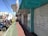 A city street view featuring several parked motorcycles and scooters near closed storefronts. The store signs include 'Fanny Calçados' and 'Piccadilly'. The sidewalk is divided into sections with green and red paving. Overhead, numerous power lines stretch across the sky.