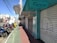 A city street view featuring several parked motorcycles and scooters near closed storefronts. The store signs include 'Fanny Calçados' and 'Piccadilly'. The sidewalk is divided into sections with green and red paving. Overhead, numerous power lines stretch across the sky.