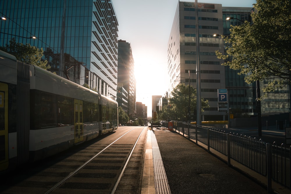 Train blanc sur la voie ferrée près des immeubles de grande hauteur pendant la journée