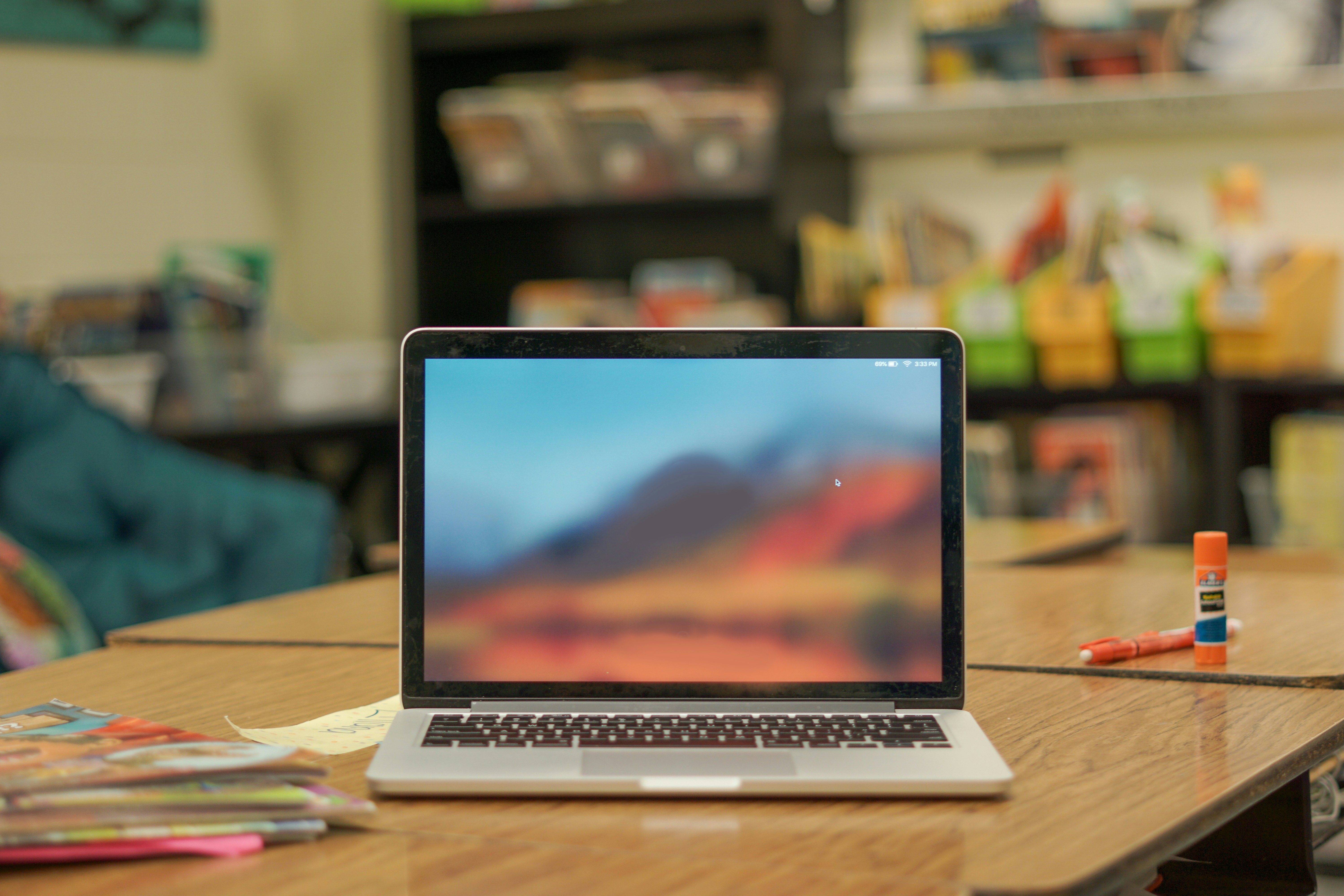 Macbook laptop computer sitting on a desk in a school classroom.