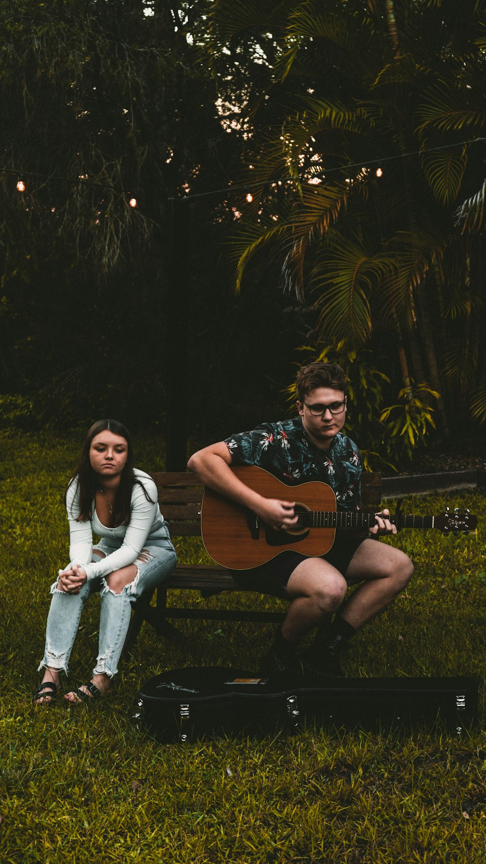 woman in black and white floral shirt sitting on brown wooden bench beside woman in white