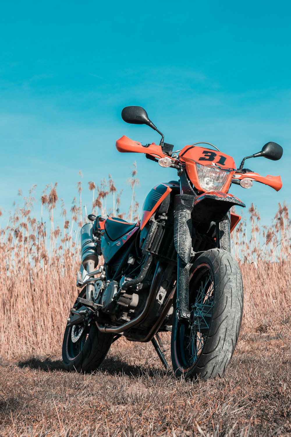 orange and black sports bike on brown grass field during daytime