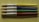 Four paintbrushes are aligned horizontally on a textured, light green surface. Each brush has a metallic ferrule and a brightly colored handle, with colors in yellow, blue, green, and red from top to bottom. The brand name 'CREATIVE PL' is printed on each handle.