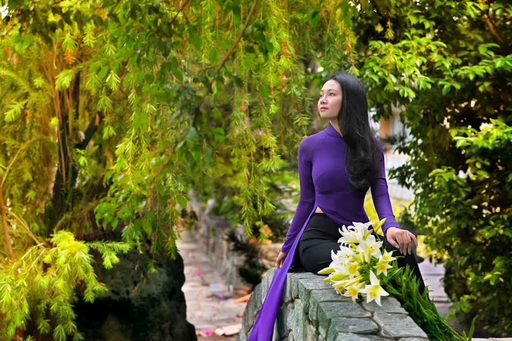 woman in purple long sleeve dress sitting on gray concrete bench