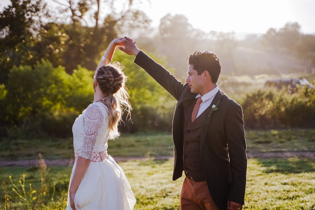 man in black suit jacket holding woman in white dress